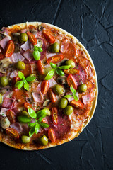 Pizza on a thin dough with olives and fresh basil