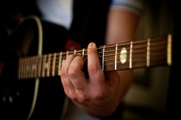 Fototapeta na wymiar Closeup of a man's hand playing a chord on an acoustic guitar. 