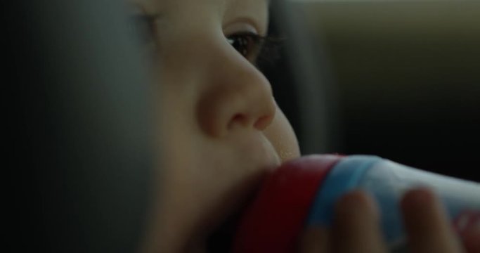 Toddler boy sipping drink in car seat - extreme close up