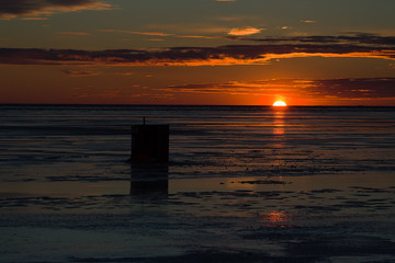Sunset over an ice fishing shed on a frozen harbor in rural Prince Edward Island, Canada.