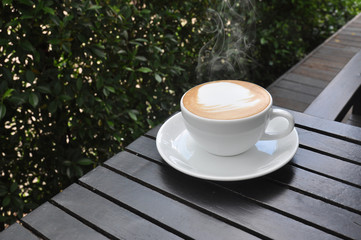 white cup of hot coffee on wooden table in coffee shop,white cup of hot coffee on wooden table on green natural background