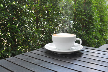 white cup of hot coffee on wooden table in coffee shop,white cup of hot coffee on wooden table on green natural background