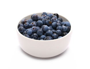 Fresh blackthorn berries pile in porcelain dish, prunus spinosa isolated on white background