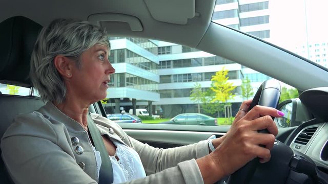 Middle aged woman drives a car in the city and scolds on other drivers 