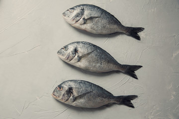 raw fish cooking and ingredients Dorado lemon herbs and spices top view on stone table