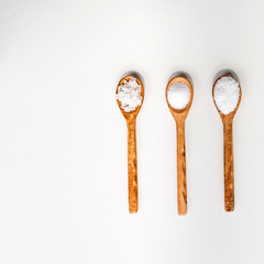 Different types of salt. Top view on black in wood spoons. Copy space..