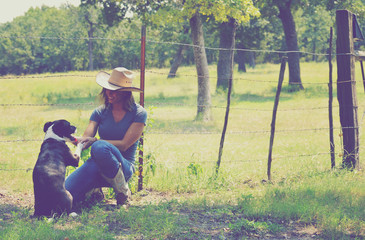 Farm scene with cowgirl and pet rescue dog shaking hands.  