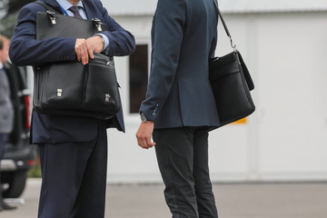 Two businessman with briefcase talking on street, close up