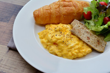 Close up breakfast set (Scrambled egg, croissant and vietnamese pork sausage with black pepper)