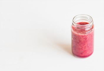 Glass of tasty red smoothie on white background table. Place for text.