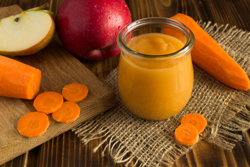 Puree with apples and carrot on the wooden background