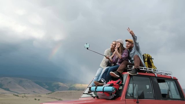 Three happy hipster young women taking selfie sitting in a vintage van during a summer road trip 20s 4k.