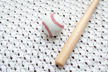 Toy baseball bat and ball on a hand made white crocheted blanket with room for copy text.