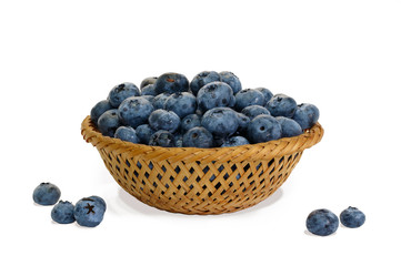 Blueberry in wicker basket and small piles on white background isolated