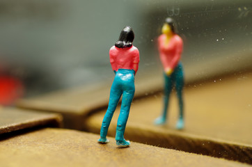 Miniature little people, woman looking herslef in a mirror, in a blurred background