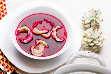 Barszcz czerwony z uszkami na bialym obrusie. Danie Wigilijne