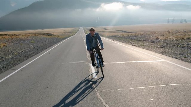 Young handsome man riding at vintage bicycle in the country road. Sporty guy cycling at the track. Male cyclist riding fixed gear bike at highway. Healthy active lifestyle 20s 4k.