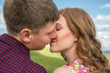 Fototapeta premium young couple kissing on a background of a landscape close-up