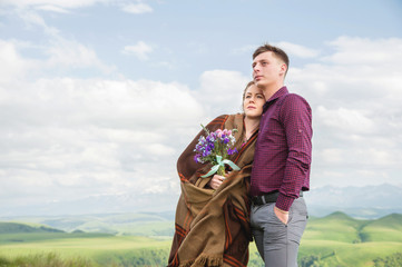 portrait of a guy with a girl covered in a blanket standing in an embrace in nature and smiling with happiness