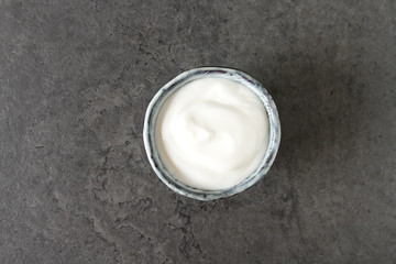 Homemade sour cream in a ceramic bowl. Dark background.