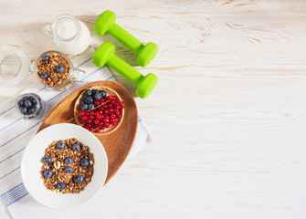 healthy food fitness and health breakfast homemade granola with nuts berries dumbbells on white background