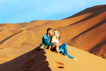 Fototapeta na wymiar Guy and girl on the sand dunes in the Sahara Desert.