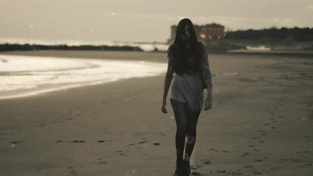 Beautiful female zombie walking on beach sad wide shot with snow