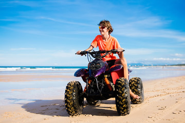 Teenager riding quad bike on beach