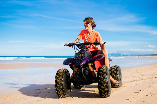 Fototapeta Teenager riding quad bike on beach