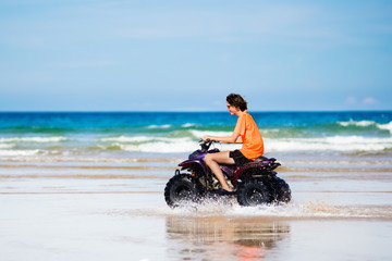 Fototapeta na wymiar Teenager riding quad bike on beach