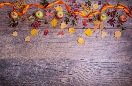 Autumn arrangement of leaves, apples and berries on a wooden background with free space for text. Top view, concept of the season