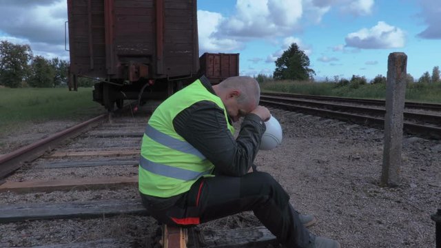 Stressful railway worker sitting on rails