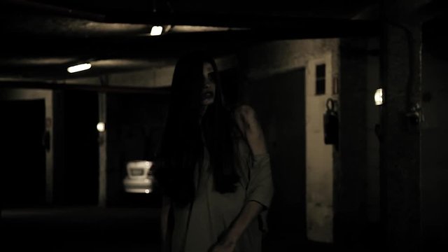 Scary female zombie walking at night in garage