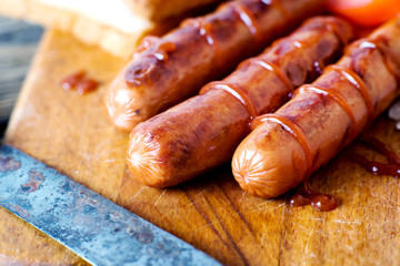 Barbecue and grill, fried meat sausages with ketchup, salt, white toast and tomatoes on a wooden board