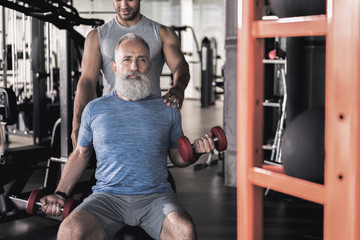 Stylish senior male spending time in athletic center with trainer