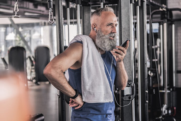 Fototapeta na wymiar Confident senior male having conversation on mobile phone in gym