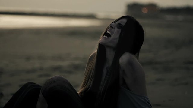 Woman zombie screaming and crying desperate on beach slow motion