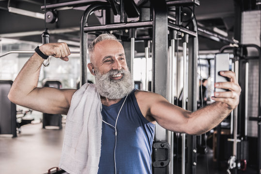 Joyful senior male making picture of himself in modern gym