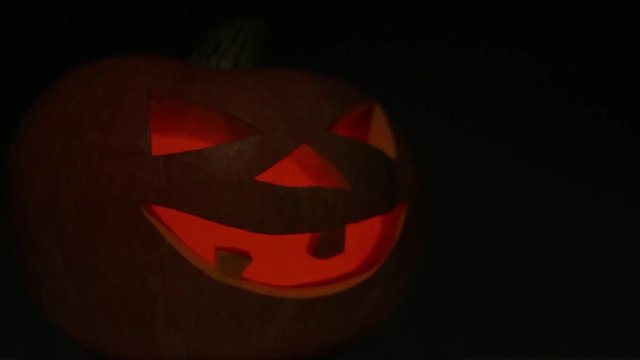Pumpkin for Halloween with a candle inside blinks and gradually becomes blurry.