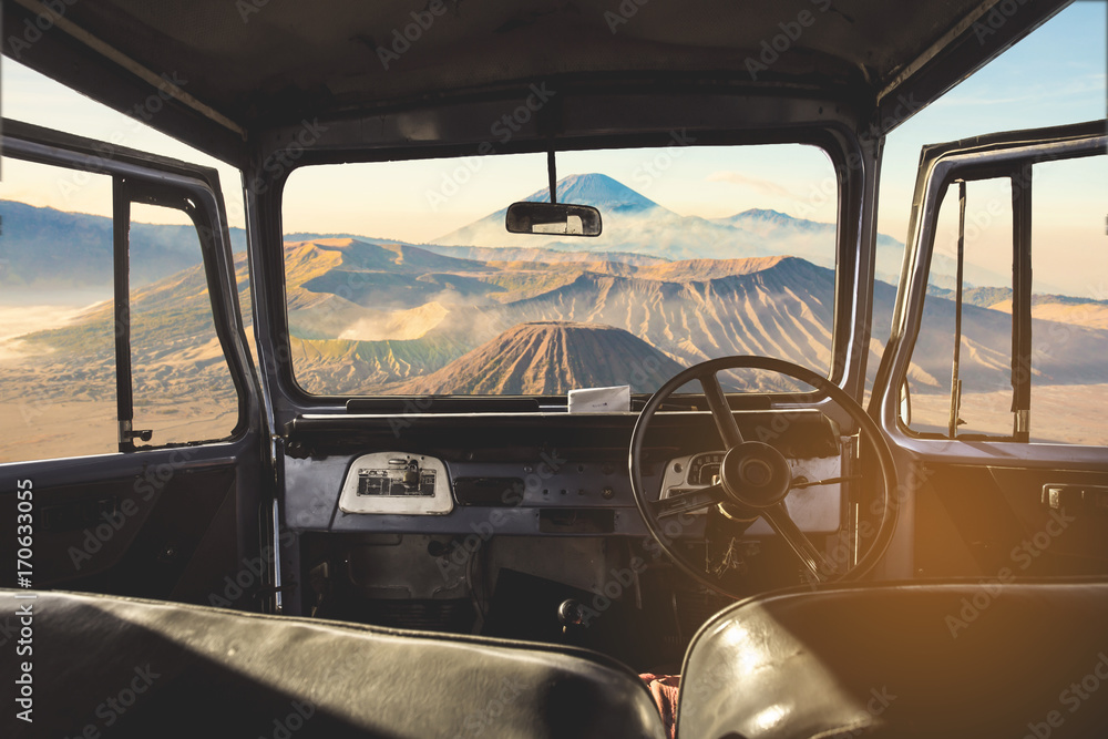 Poster view on the dashboard of the car. bromo mountains is in front of the car.