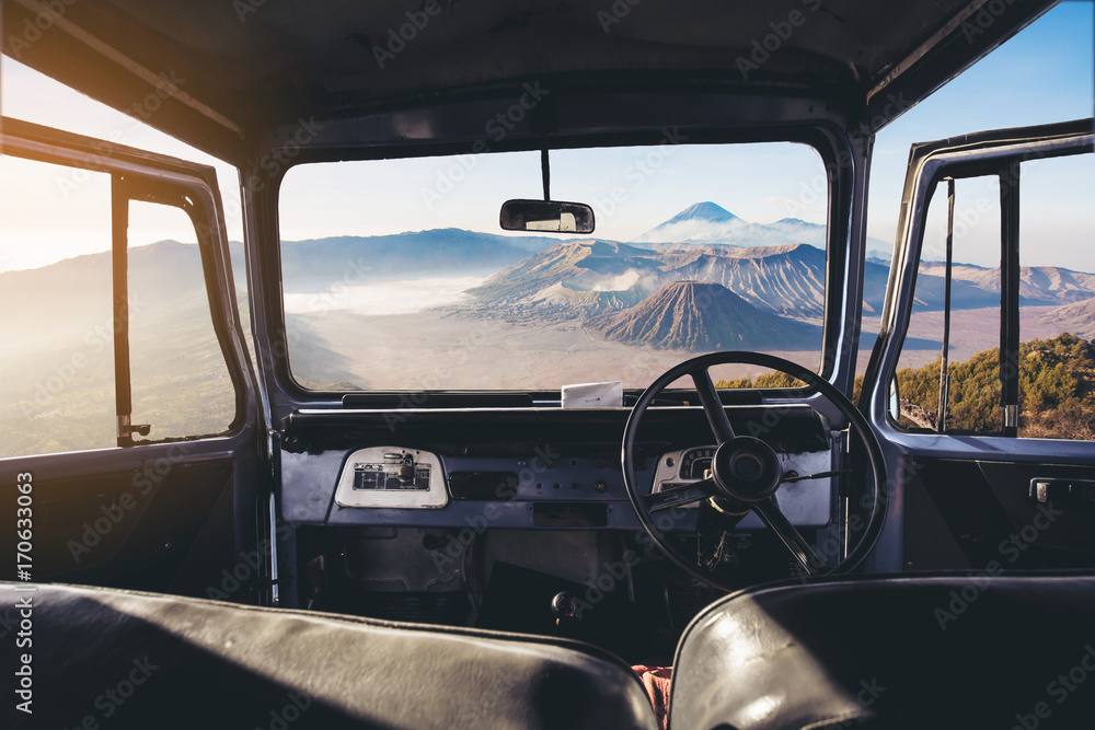 Poster view on the dashboard of the car. bromo mountains is in front of the car.