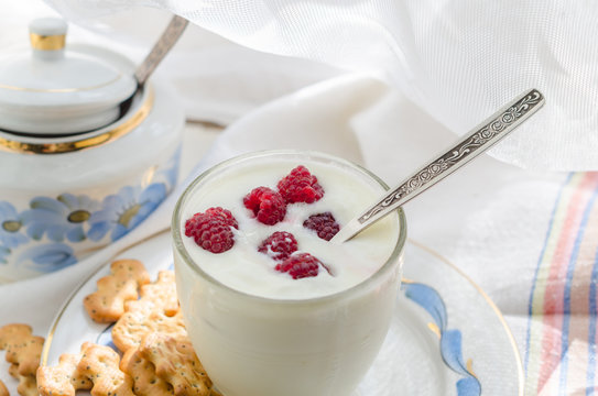 Milk yogurt with raspberries in a transparent glass with a spoon