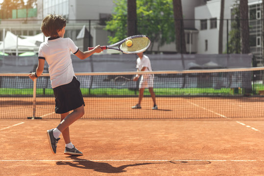 Male child playing tennis with opponent