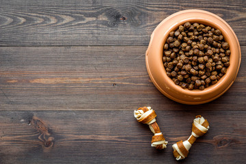 pet care with dry food for pet - dog in plastic bowl on wooden background top view space for text