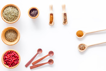 Variety of spices and dry herbs in bowls on white kitchen table background top view mock-up