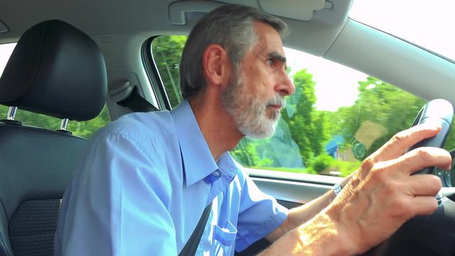 Senior man drives a car in the city and scolds on other drivers 