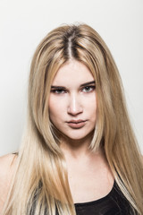 Naklejka premium Close-up portrait of a young beautiful blonde girl on a light background. A woman with different emotions on her face.
