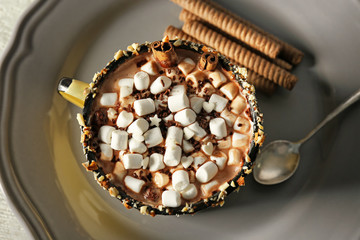 Cup of cocoa with marshmallows on plate, closeup