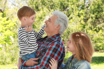 Obraz na płótnie Canvas Cute happy children with grandfather in spring park