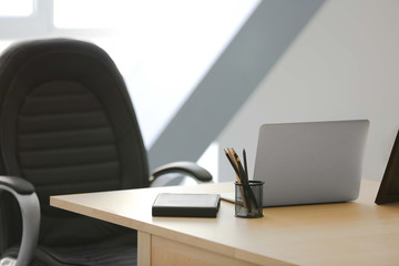 Wooden table with laptop and chair in office